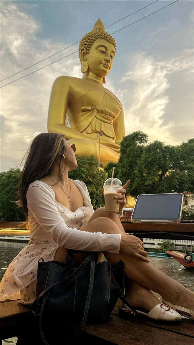Steph at a cafe near a golden Buddha statue
